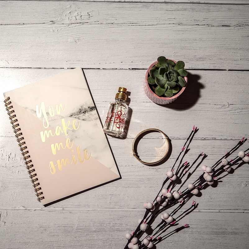 Simple steps to the ideal self care road trip - flat lay including note book, plants and perfume