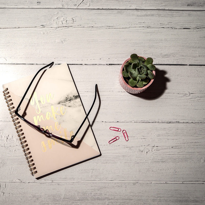 Maintain your self care routine - image is of a flatlay overlooking a notebook and glasses next to a cactus plant