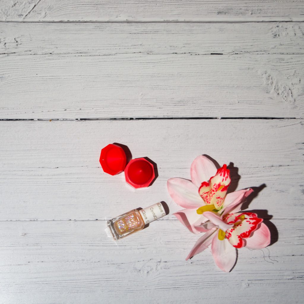 Positivity during lockdown - Flat lay image of pink flowers, nail varnish and pink lip balm.